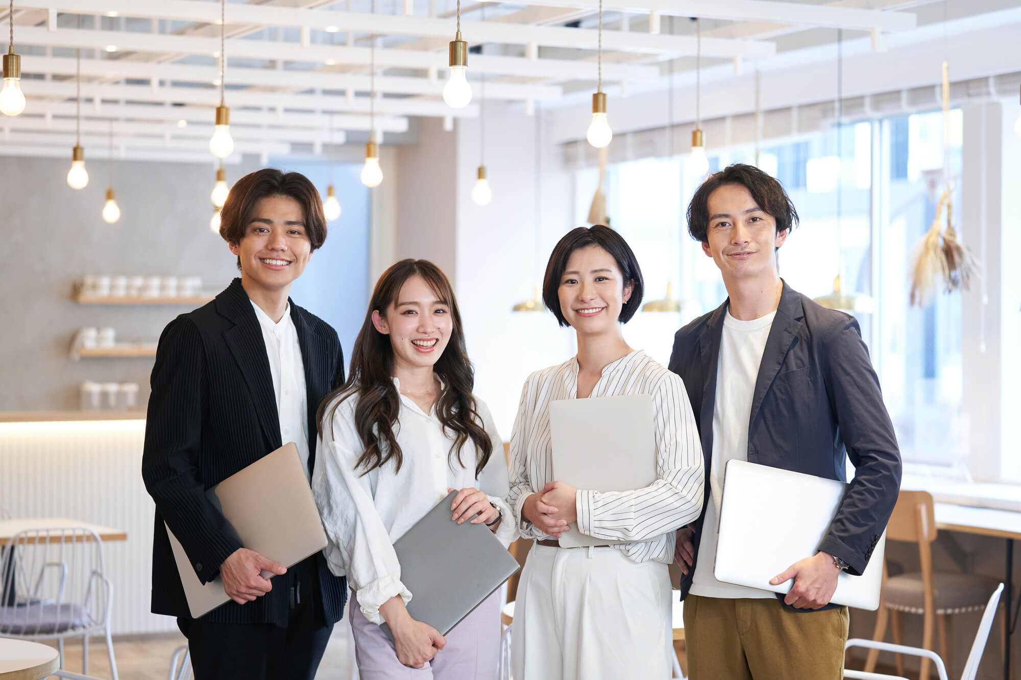 画像：パソコンを持った4人の男女